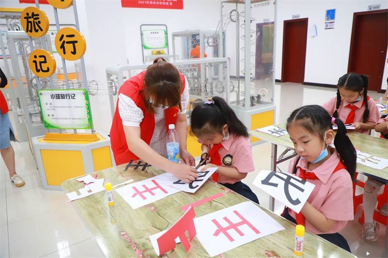 2021年7月10日，鄂州市科协组织落驾坪小学学生在鄂州市科技馆开展社会主义核心价值观系列活动，图为开展的红色剪影圆梦中华剪纸活动，志愿者指导同学们.jpg